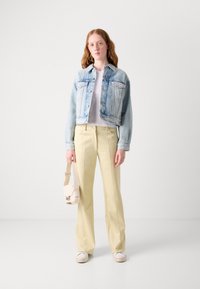 Afgekorte lichtblauwe denimmantel, witte t-shirt, lichtgele op maat gemaakte broek, met een beige schoudertas, witte sneakers. Eenvoudig ontwerp.