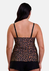 Débardeur en imprimé léopard noir avec de fines bretelles réglables et une texture lisse et semi-transparente, associé à un short noir.