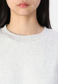 Lichtgrijze sweatshirt van katoenmix, met een ribgebreide ronde hals en een klein wit geborduurd logo op de borst.