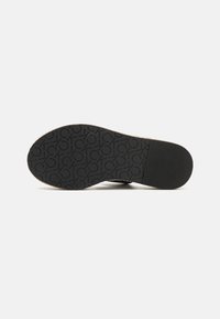 Suola di scarpa in gomma nera con texture a motivo, caratterizzata da design circolari in rilievo e una sezione anteriore liscia. Progettata per resistenza e trazione.