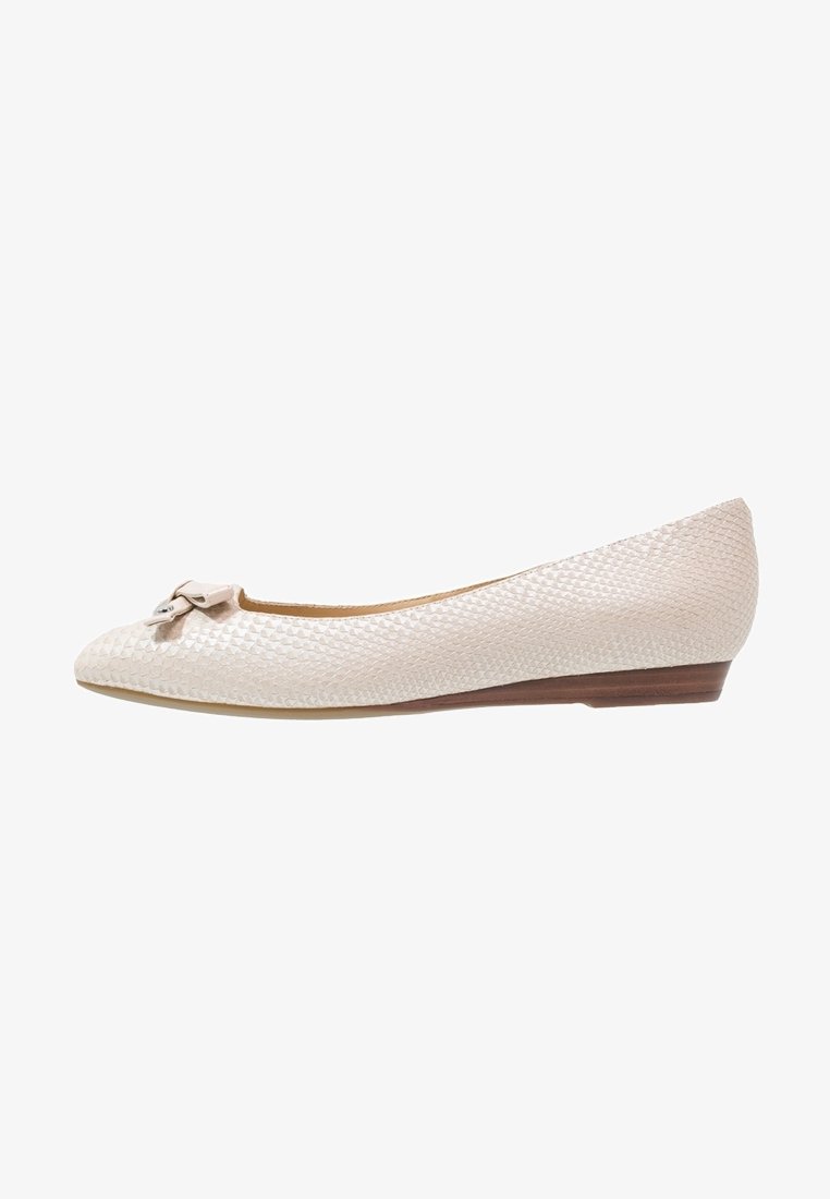 Ballerine beige texturée avec un petit nœud et un détail argenté sur le bout, et un petit talon en bois brun.