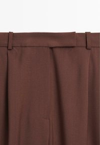 Braune maßgeschneiderte Hose mit glatter Textur, flacher Vorderseite, Gürtelschlaufen und subtilen Falten an der Taille.