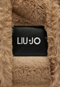 Nepbont tas in lichtbruin met een zachte textuur. Voorzien van een zwart leren label met daarop "LIU•JO" in witte letters.