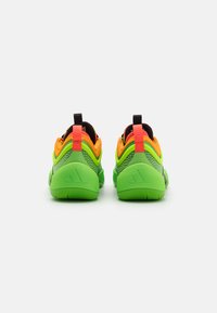Groene en oranje sportieve schoenen met een gestructureerd mesh en rubberen zolen. Beschikt over een zwarte hielinzet en heldere accenten op het bovenwerk.