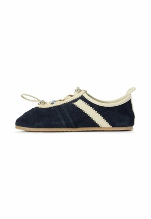 Scarpa morbida da bambino color blu navy e beige con asola per il laccio e striscia beige a zigzag sul lato, vista dal lato esterno.