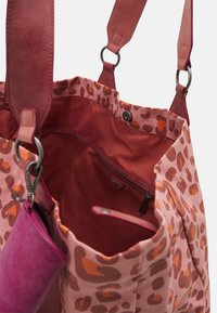 Borsa tote in tessuto rosa con un motivo leopardato. Presenta un interno rosso, una tasca con zip e manici in pelle con anelli in metallo.