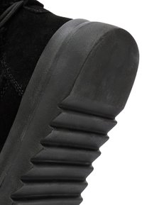 Zwarte suède laars met een gestructureerde zwarte rubberen zool met hoekige ribbels. Het bovenwerk is zacht, met minimaal zichtbare stiksels.