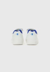 Baskets blanches avec doublure intérieure bleue et logo "C" bleu à l'arrière, présentées de l'arrière sur un fond blanc uni.