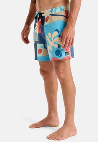 Schwimmshorts in lebhaftem Blau mit abstrakten Mustern in Rot, Creme und Marineblau. Mit elastischem Bund und schwarzem Kordelzug sowie Seitentaschen.