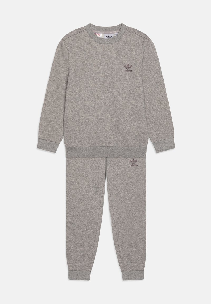 Siva dukserica s odgovarajućim sivim trenerkama, oboje izrađeno od mekanog materijala. Ima rebraste manžete i mali logo na grudima i butinama.