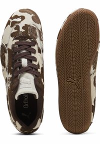 Sneaker con motivo di pelle di mucca marrone e crema, lacci marroni, suole in gomma e dettagli testurizzati. Presenta il logo sulla linguetta e sulla suola.