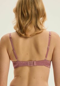 Różowy biustonosz z regulowanymi ramiączkami i fakturowanym kwiatowym wzorem. Posiada zapięcie na haftkę z tyłu. Miękki, gładki materiał.