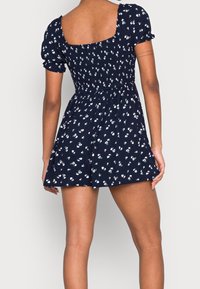 Námořnické modré květinové šaty s krátkými nabíranými rukávy, upnutým korzetem, elastickým zadním dílem a rozšířenou sukní s nařaseným pasem.