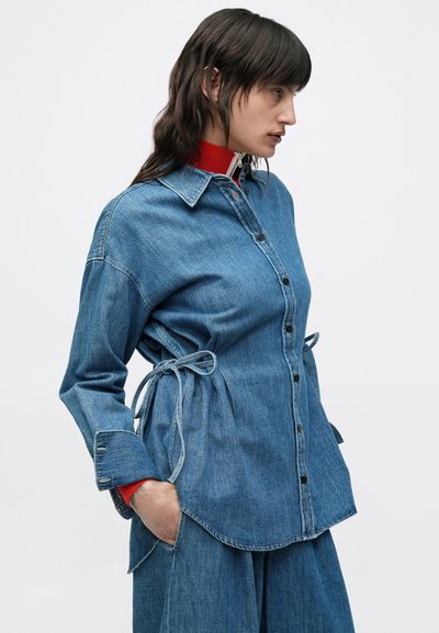 Πουκάμισο από τζιν με εφαρμοστή γραμμή, ανοιχτό μπλε χρώμα, μακριά μανίκια, κούμπωμα με κουμπιά και ρυθμιζόμενους δεσίματα στη μέση.