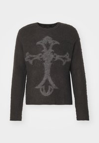 Pull marron foncé en tissu pelucheux à manches longues, avec un grand motif de croix gothique gris clair sur le devant.
