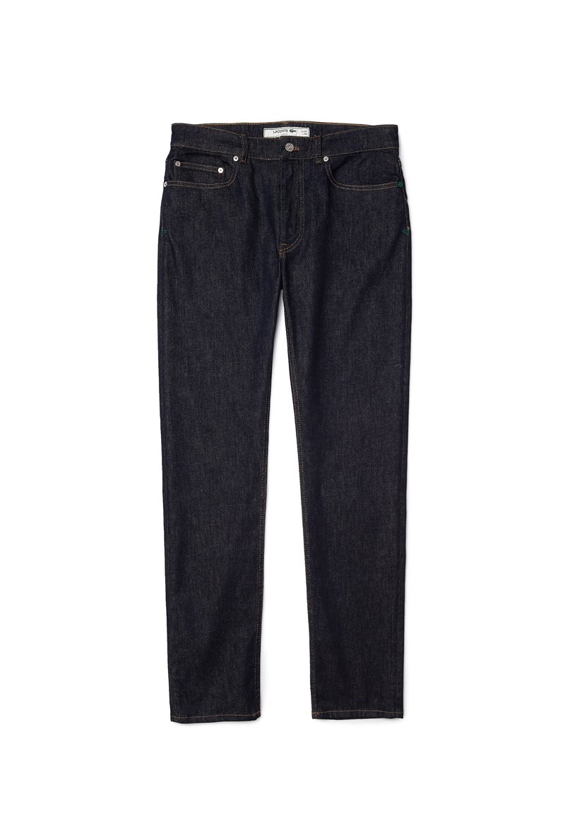 Dunkelblaue Skinny-Jeans. Fünf Taschen, goldene Nähte und ein Markenlabel am Bund. Robuster Stoff und glatte Textur.