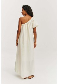 Krémové maxi šaty bez ramienok s jedným nariaseným rukávom a nariaseným výstrihom; mäkká, splývavá látka s uvoľneným strihom.