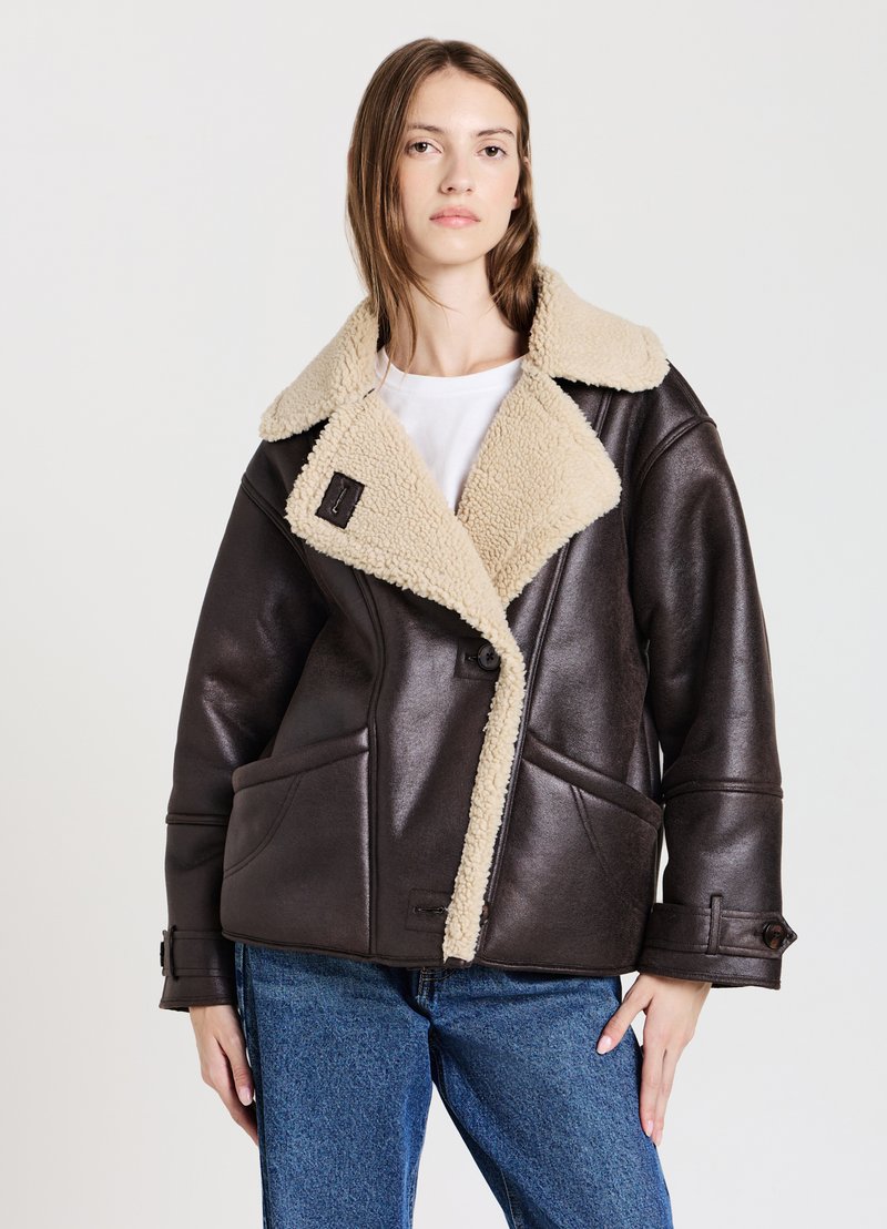 Giacca in ecopelle marrone con colletto in shearling beige, design doppiopetto, grandi tasche e dettagli con bottoni. Finitura texturizzata.