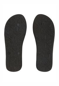 Semelles de chaussures en caoutchouc noir présentant un motif texturé de formes géométriques et de petits détails circulaires pour une meilleure adhérence.