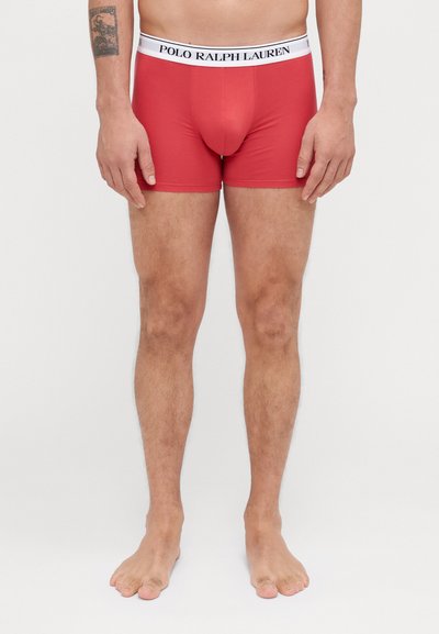 Boxeri roșii dintr-un material elastic, având un brâu elastic alb cu logo-ul "POLO RALPH LAUREN", design ajustat și textură netedă.