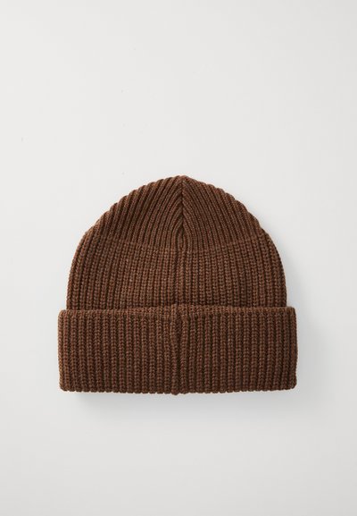 Brūns adīts beanie ar ribotu faktūru, kas piedāvā pabrīņu malu. Augšdaļai ir gluda, noapaļota forma ar vienmērīgu šuvju izpildi.