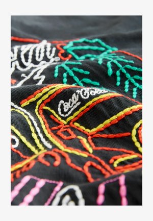 Black fabric featuring colorful embroidery in white, green, red, orange, yellow, and pink, with intricate designs and textures.