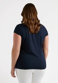 Camiseta de color azul marino, de manga corta, con una textura suave y lisa y un corte relajado, que presenta un sutil detalle en los hombros.