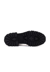 Suela de zapato de caucho negro con un dibujo profundo, presentando un patrón en forma de diamante y acentos angulares para mejorar el agarre y la durabilidad.
