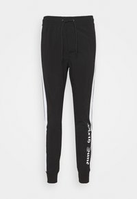 Svart joggebukse med elastisk midje og snor. Har hvite stripe på siden og tekstdetalj på venstre ben. Tapered fit.