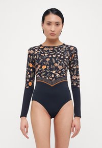 Maillots de bain noir à manches longues présentant un motif floral orange sur le torse, avec un bas noir uni et une bordure contrastée en crochet.