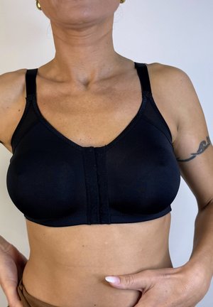 Sujetador deportivo negro con cierre frontal, tirantes ajustables y una tela lisa y elástica. Presenta un diseño simple y funcional sin adornos.