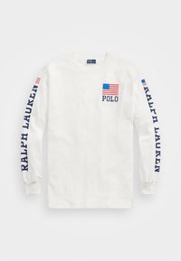 Vit långärmad T-shirt i bomull, med en framficka som har en liten amerikansk flagga och "Polo," samt "RALPH LAUREN" tryckt på båda ärmarna.