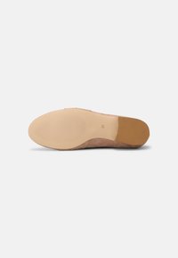 Semelle de chaussure en daim marron avec un motif structuré, présentant du caoutchouc beige lisse au niveau des orteils et du talon pour l'adhérence et la durabilité.