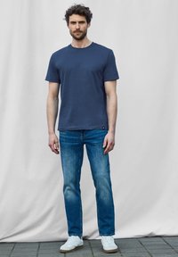 Námořnický crewneck tričko, krátké rukávy; nošeno s světle modrými rovnými džíny a bílými teniskami; hladký materiál a ležérní střih.