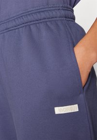 Pantalons de jogging bleu marine en tissu doux, dotés d'une taille élastique et de poches latérales, avec une étiquette blanche affichant "BORG."