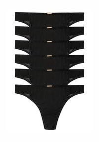 Set di lingerie nera con perizoma, realizzato in materiale trasparente, con cinturini sottili e un accento in hardware dorato. Sette pezzi disposti ordinatamente.