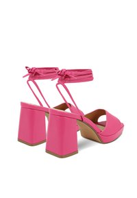 Sandali con tacco a blocco rosa, presentano una tomaia in pelle liscia, punta aperta e sottili cinturini alla caviglia legati a fiocco. Design del tacco quadrato.