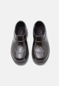 Tamancos pretos em cabedal brilhante com pontas arredondadas, textura suave e palmilha acolchoada. Apresenta uma altura baixa no tornozelo e solas texturizadas.