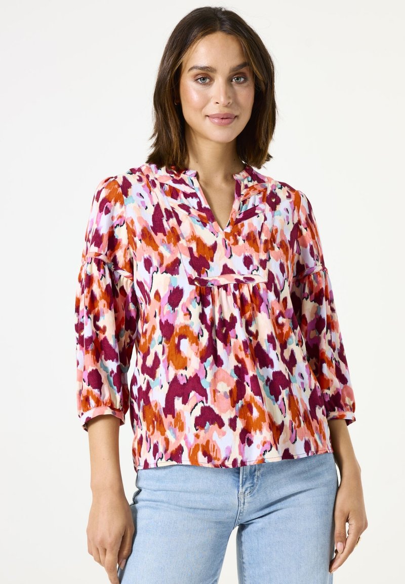 Blusa multicolorida de tejido ligero con escote en V, mangas tres cuartos y corte holgado. Presenta un patrón abstracto en rosa, naranja y púrpura.