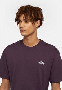 Lila kortärmad t-shirt i bomull med en vit Dickies-logotyp på bröstet och en klassisk rundhalsdesign.
