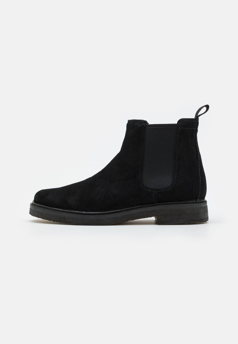 Bottines Chelsea en daim noir avec des panneaux élastiques sur les côtés, une languette et une semelle texturée. Design classique avec un bout arrondi et un style minimaliste.