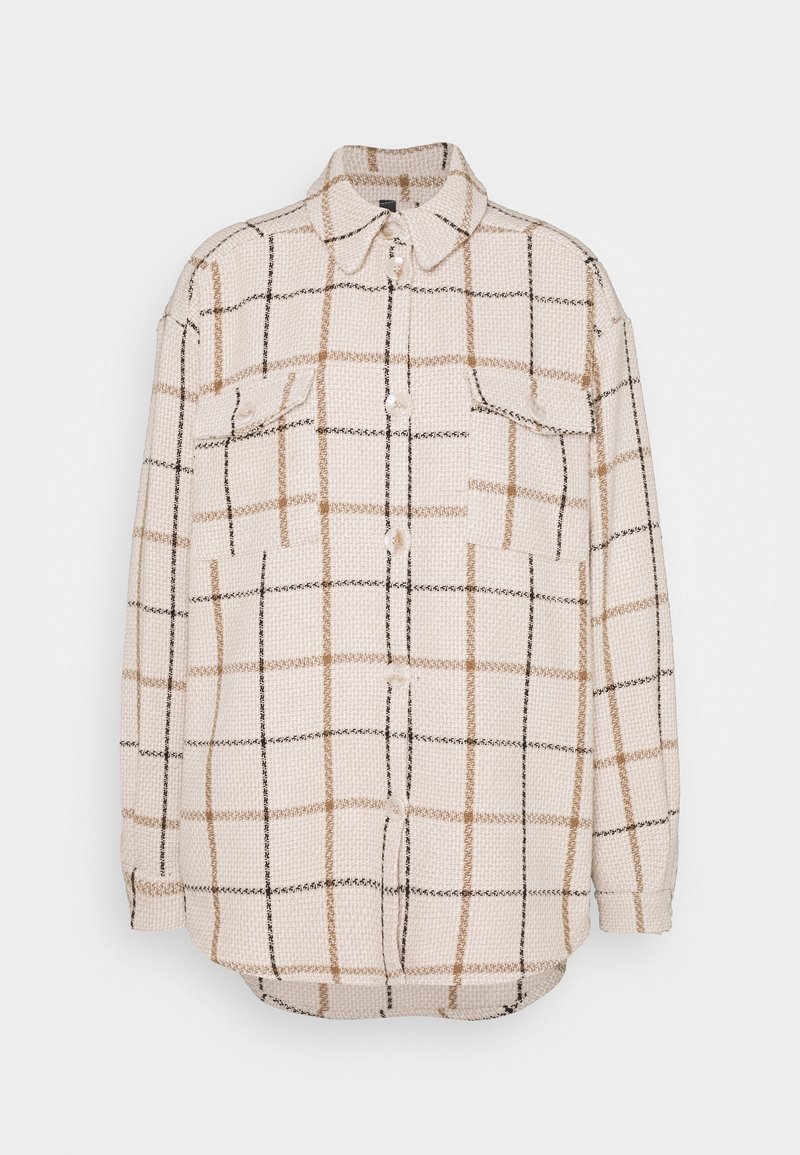 Veste crème texturée à boutons, motif à carreaux marron et noir, deux poches poitrine à rabat et col pointu.