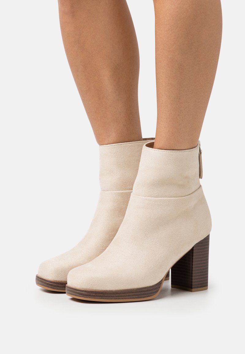 Beige semišové kotníkové boty s kulatou špičkou, s manžetou a se zúženým dřevěným podpatkem. Boční zip pro snadné obouvání.