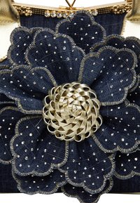 Denim virágkitűző arany szőtt középpel, sötétkék szirmokkal, kicsi ezüst szegecsekkel és díszes arany varrással kiemelve.