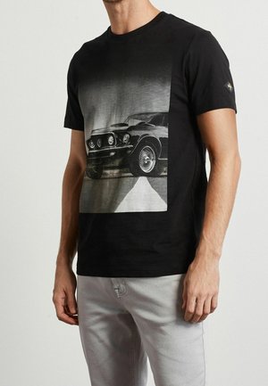 Black t-shirt featuring a large grayscale graphic of a classic car. The fabric is smooth with a crew neck and short sleeves.