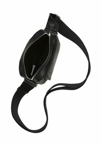 Sac à épaule en cuir noir avec un haut zippé, de forme rectangulaire mince et une bandoulière en tissu ajustable. L'intérieur présente un revêtement noir.