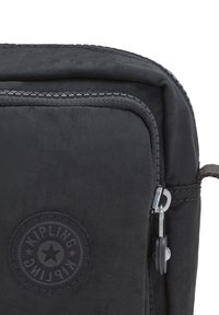 Borsa nera in nylon con tessuto testurizzato, logo circolare "Kipling", zip argentata e dettagli grigio scuro. Design semplice e angolare.