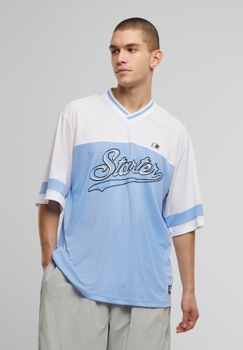 Lys blå og hvit kortermet jersey med V-hals. Har "Starter" logo i kursiv, kontrasterende striper på ermene, og en løs passform.