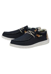 Scarpe slip-on navy con tomaia in tessuto testurizzato, suola bianca a contrasto, lacci beige e fodera interna con motivo. Accentuate da linghette in legno.