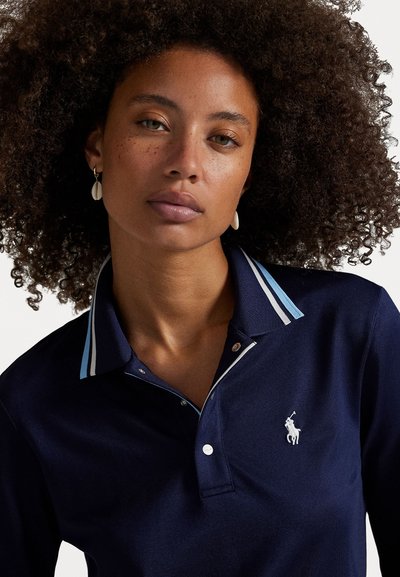 Navy polo shirt with a textured fabric, contrasting light blue stripes on the collar, and an embroidered logo on the left chest.